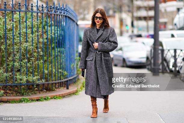 Christine Centenera wears sunglasses, a gray striped long wool coat, brown leather boots, outside Balmain, during Paris Fashion Week - Womenswear...