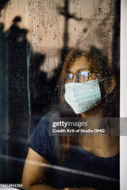 woman looking through the wet window during stay home while covid-19  back - looking through window covid stock pictures, royalty-free photos & images