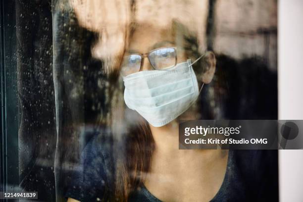 woman looking through the wet window during stay home while covid-19  back - lockdown stock pictures, royalty-free photos & images