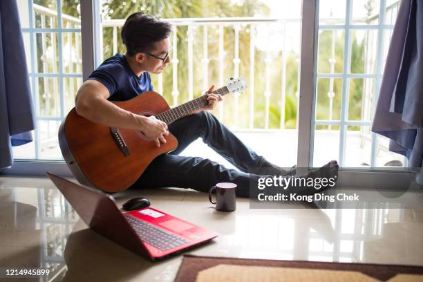 un hombre de negocios chino de asia trabaja desde casa. tocando la guitarra durante el tiempo de descanso del café. - autor de canciones fotografías e imágenes de stock