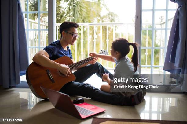 an asia chinese businessman work from home. playing guitar during coffee break time. daughter sitting beside and spending wonderful time with him - chinese music imagens e fotografias de stock