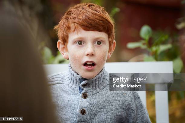 surprised boy looking away while sitting in yard - faszination stock-fotos und bilder