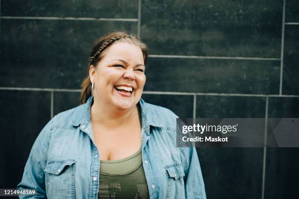 smiling mature woman standing against wall - body positive stock pictures, royalty-free photos & images