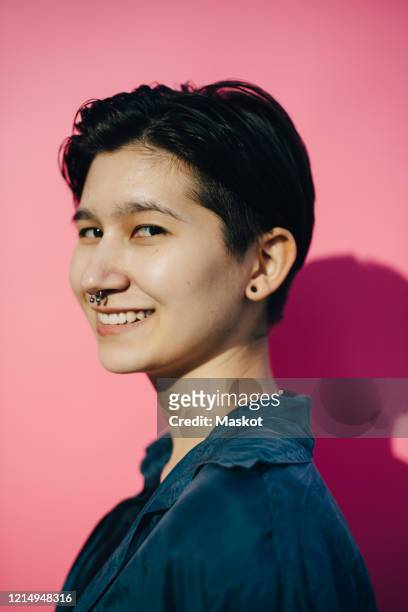 portrait of smiling young woman against pink background - non binary stereotypes stock pictures, royalty-free photos & images