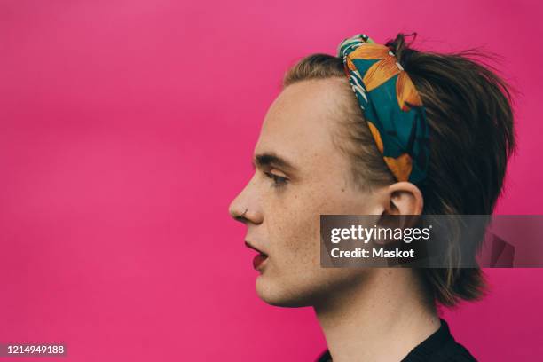 side view of confident young man standing against pink background - nose piercing stock pictures, royalty-free photos & images