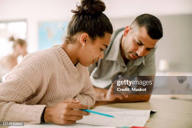 teenager studying with professor while sitting in classroom - professor particular imagens e fotografias de stock