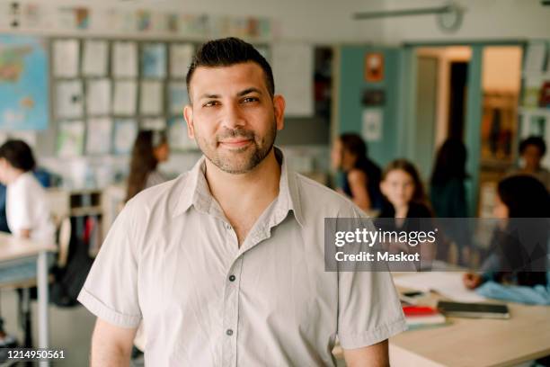 portrait of smiling male tutor standing in classroom - teacher studio portrait stock pictures, royalty-free photos & images