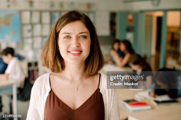 portrait of smiling female teacher standing in classroom - teacher studio portrait stock pictures, royalty-free photos & images