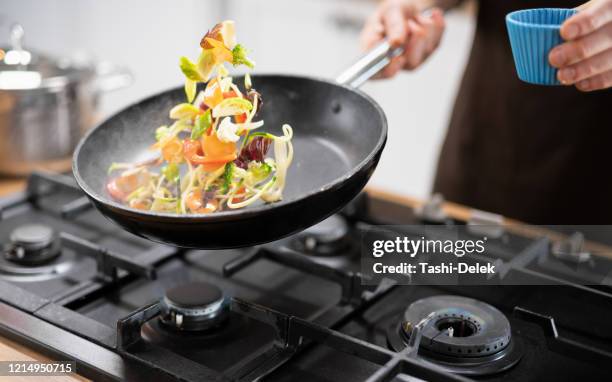 chef profesional tossing food - salteado fotografías e imágenes de stock