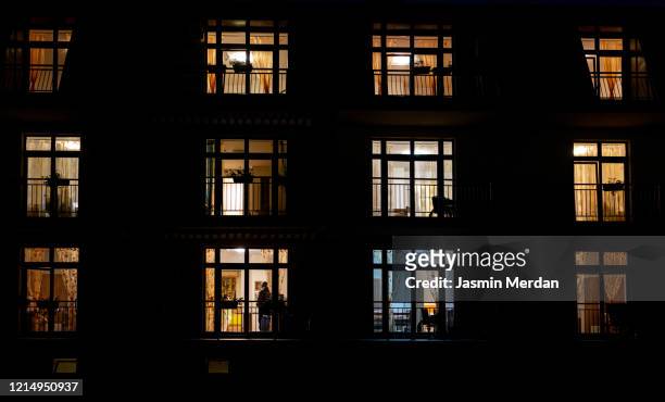 illuminated windows of night house with people inside - verlicht stockfoto's en -beelden