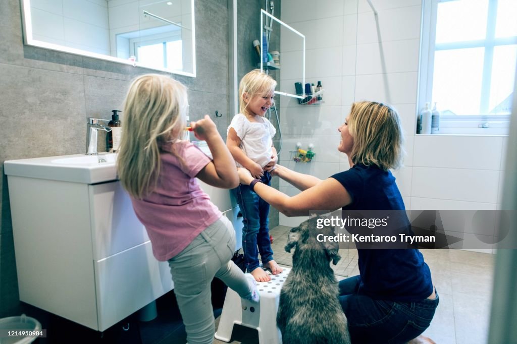 Smiling mother bonding while kneeling in bathroom by dog at home