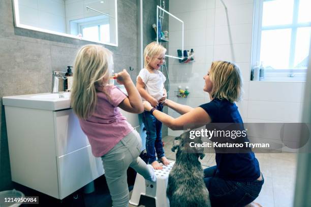 smiling mother bonding while kneeling in bathroom by dog at home - eén dier stockfoto's en -beelden