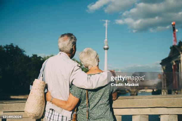 rear view of senior couple with arm around looking at television tower from bridge in city - berlin travel stock pictures, royalty-free photos & images