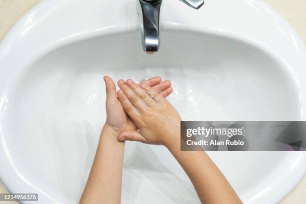 young child washes his hands with soap and water at these important times. - child washing hands stock pictures, royalty-free photos & images