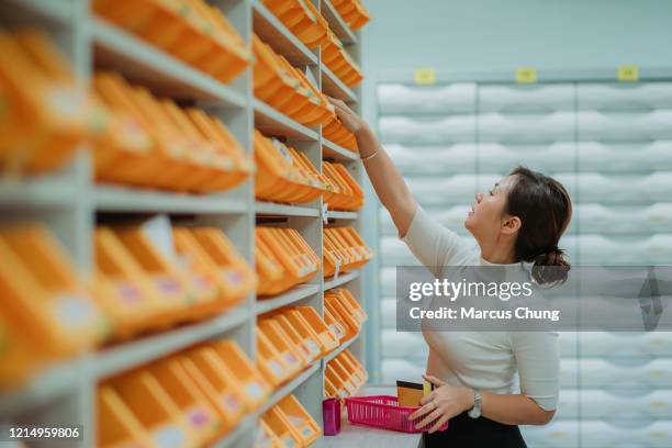 asian chinese female pharmacist pickup medicine from the tray preparing for their patient at pharmacy hospital - medical supplies stock pictures, royalty-free photos & images