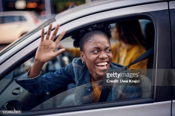 young woman in car - winken stock-fotos und bilder