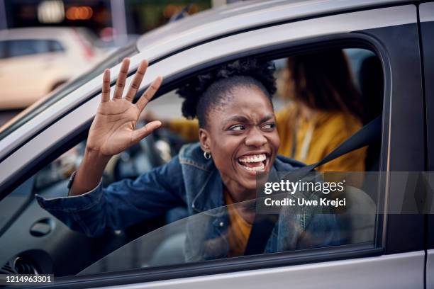 young woman in car - waving hand stockfoto's en -beelden