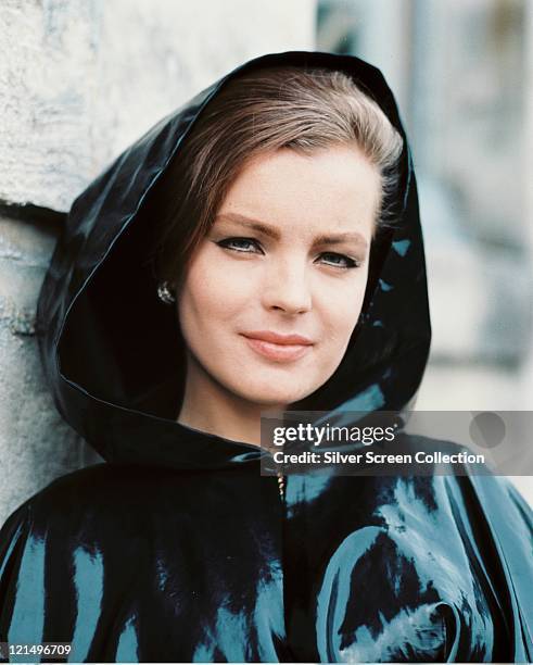 Romy Schneider , Austrian actress, wearing a dark plastic raincoat, with the hood up, circa 1970.