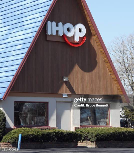 Solitary worker sits at the window at a IHOP restaurant that is open for take-out business only on March 26, 2020 in Huntington Station, New York....
