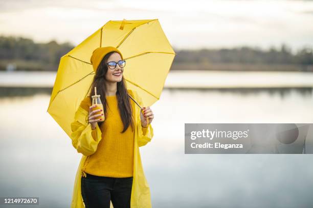 frau hält regenschirm und trinksaft - cocktail umbrella stock-fotos und bilder