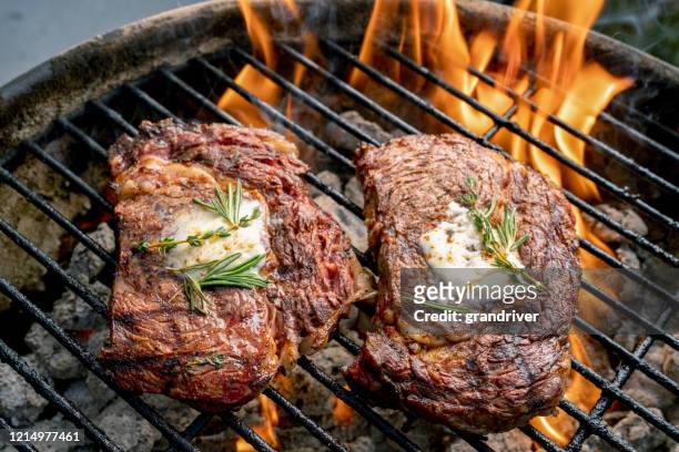 due deliziose bistecche di ribeye succose spesse su una griglia fiammeggiante - grill fire meat foto e immagini stock