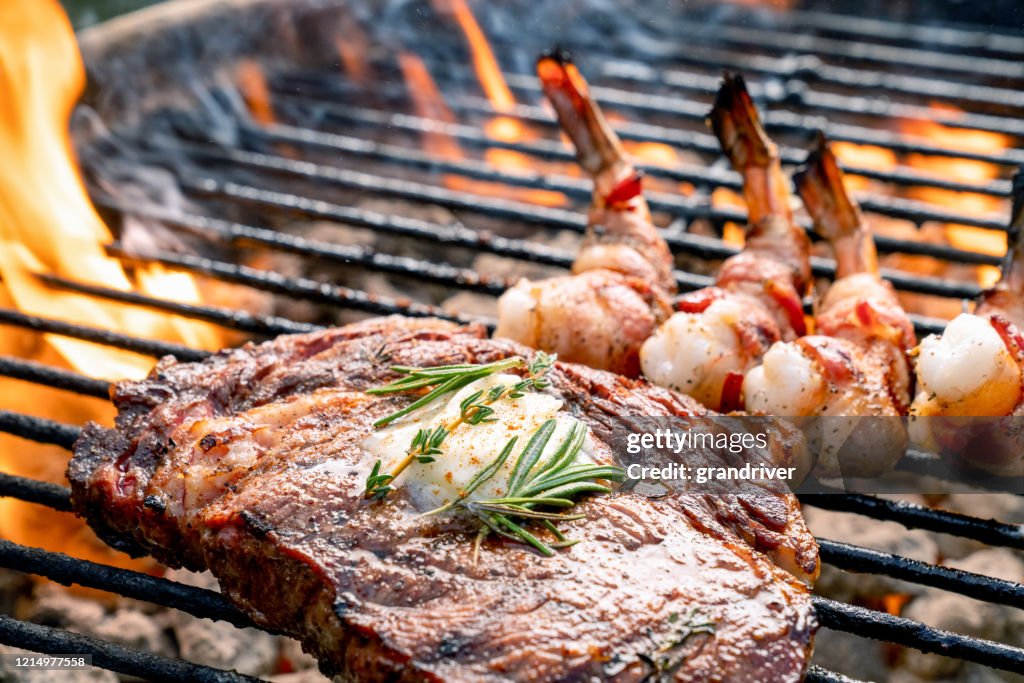 A Delicious Ribeye Steak And Bacon Wrapped Shrimp On A Flaming Hot Grill
