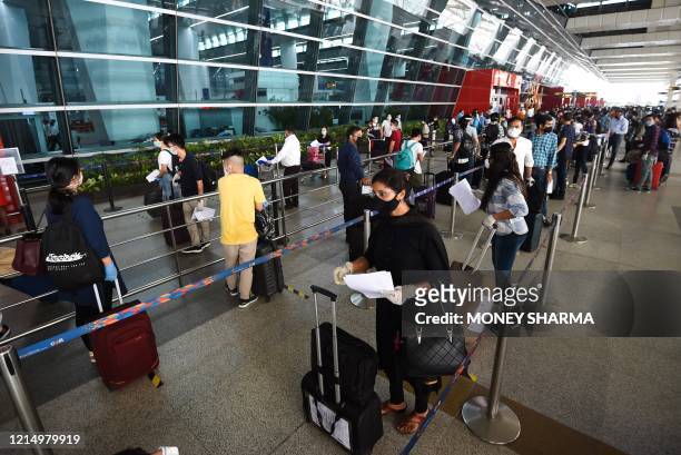 Passengers lineup to check-in outside the Indira Gandhi International airport during the first day of resuming of domestic flights after the...