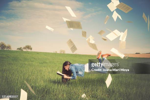 young girl floats in the air, while reading a book.  dreams, fantasy and reading concept. - paper blowing stock pictures, royalty-free photos & images