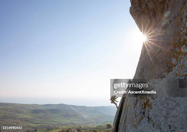 de klimmers van de berg beklimmen rotsgezicht bij zonsopgang - zekeren stockfoto's en -beelden