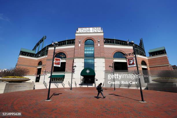 Woman walks past the home plate entrance of Oriole Park at Camden Yards on March 26, 2020 in Baltimore, Maryland. The Baltimore Orioles and New York...