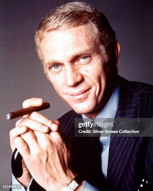 Steve McQueen , US actor, wearing a dark blue pin stripe jacket, a blue shirt and a black tie, and holding a cigar in a publicity portrait issued for...