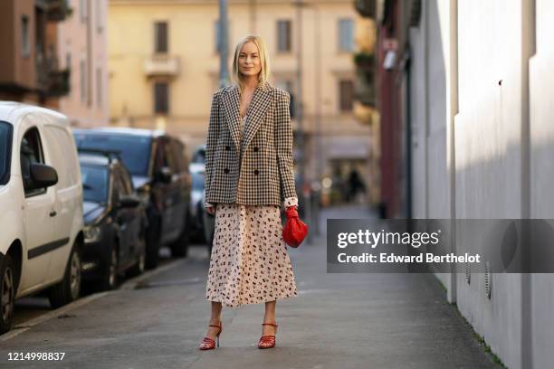 Thora Valdimars wears a black and white checked pattern oversized blazer jacket, a white floral print low neck dress, a red woven leather Bottega...