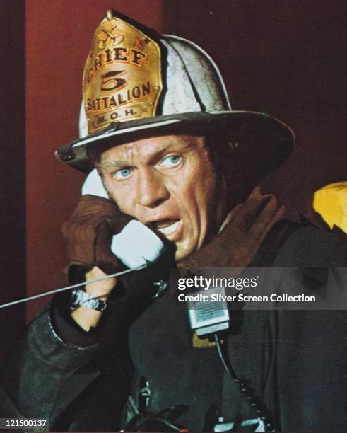 Steve McQueen , US actor, speaking into a white telephone receiver, and wearing a firefighter's costume in a publicity still issued for the film,...