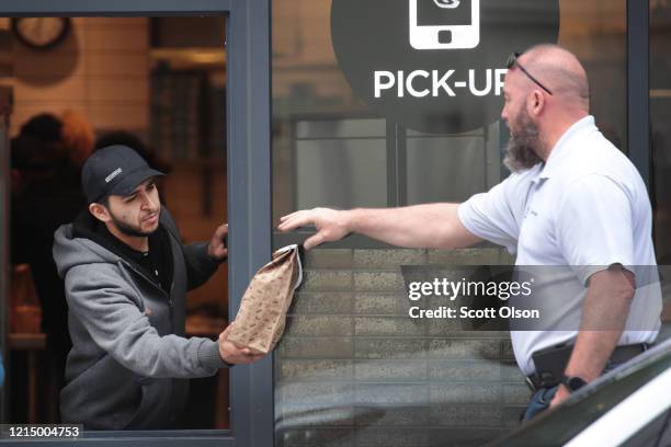 Worker at a Chipotle restaurant waits on customers through a window on March 26, 2020 in Chicago, Illinois. Illinois Gov. J.B. Pritzker has ordered...
