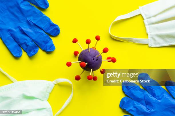 covid-19, blue plastic gloves and face mask on a yellow background. - máscara quirúrgica fotografías e imágenes de stock