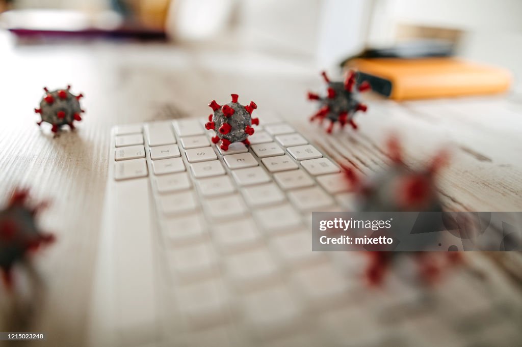 Modell des Corona-Virus auf Schreibtisch und Tastatur im Büro