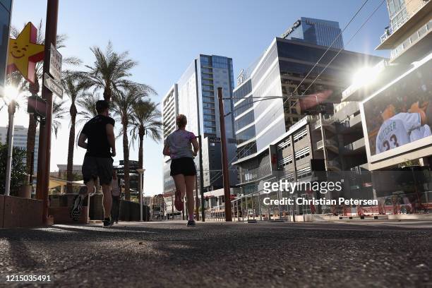 Man and woman run through downtown on March 26, 2020 in Phoenix, Arizona. The Coronavirus pandemic has spread to many countries across the world,...