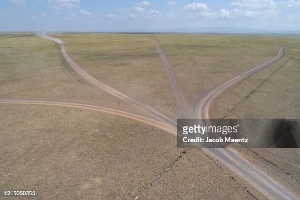 aerial view of an off-road vehicle traveling on dirt roads of the gobi desert. - fork in the road stock-fotos und bilder