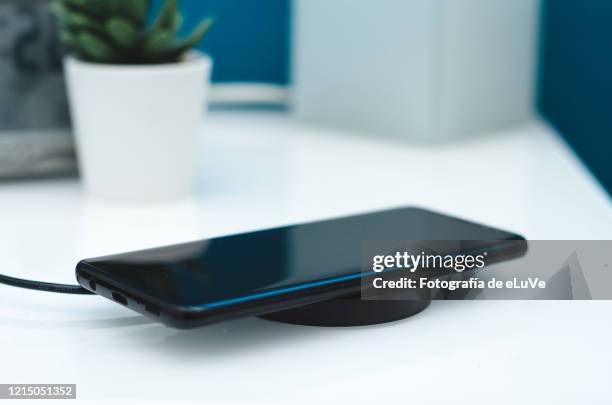 charging mobile phone with wireless device - mobile device on table stockfoto's en -beelden