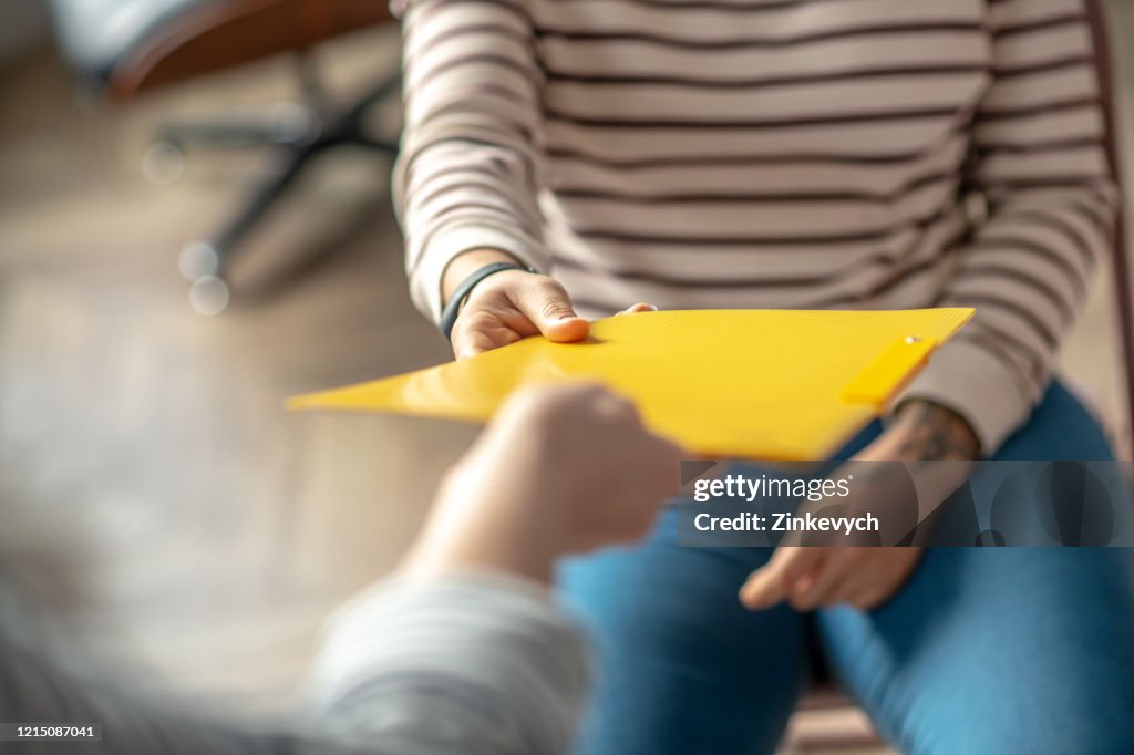 Close up picture of womans hand passing the folder