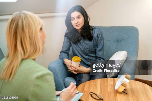 positive blonde middle-aged woman psychologist talking to girl patient - kid middle finger stock-fotos und bilder