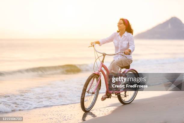 在沙灘上騎自行車的快樂女人 - mecklenburg vorpommern 個照片及圖片檔