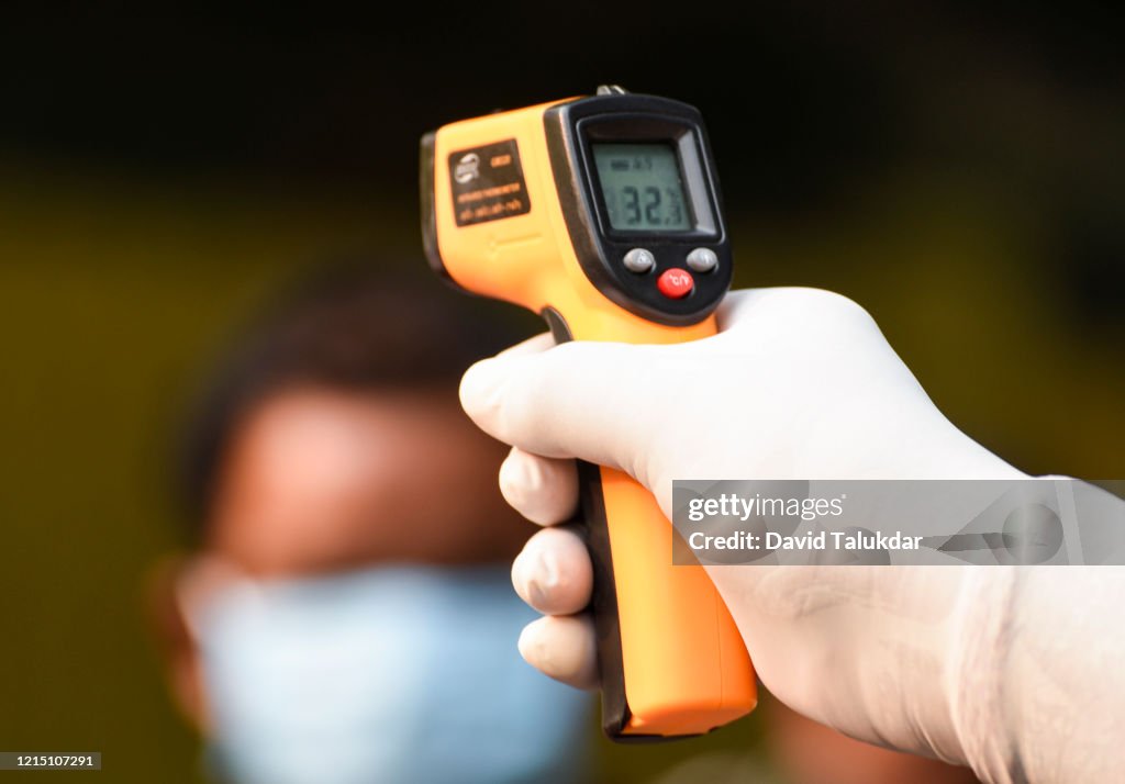 Police personnel thermal screening a person before entering to Governor House