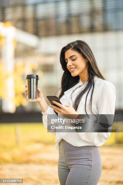 happy businesswoman using phone and drinking coffee - good news stock pictures, royalty-free photos & images