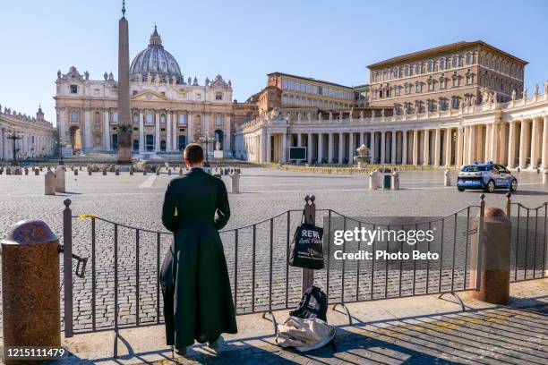 a catholic priest prays on the edge of st. peter's basilica square closed to tourists due to the covid-19 lockdown - spartan cruiser stock pictures, royalty-free photos & images