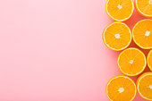 Bright halves of oranges. Fresh fruits. Empty place for text on light pink table background. Pastel color. Closeup. Top down view.