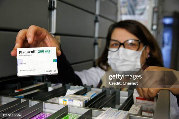 Pharmacy employee wearing a protective mask shows a box of Plaquenil on March 27, 2020 in Paris, France. French Minister of Health, Olivier Veran, in...