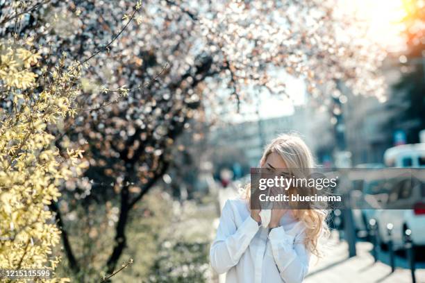 woman sneezing in the blossoming garden - hayfever stock pictures, royalty-free photos & images