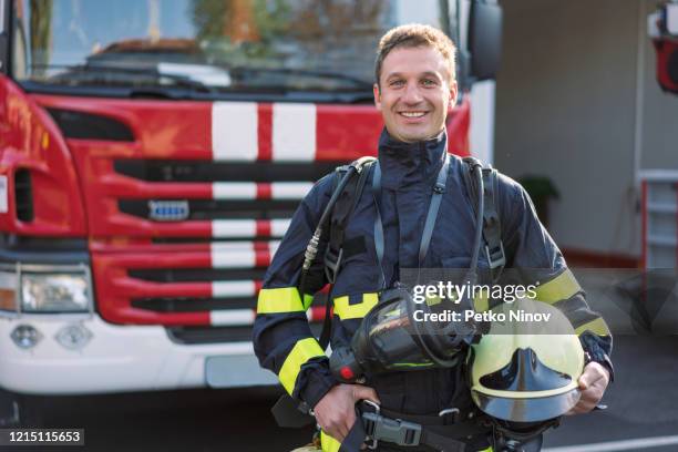 portrait of cheerful mid adult firefighter on duty - quartel de bombeiros imagens e fotografias de stock