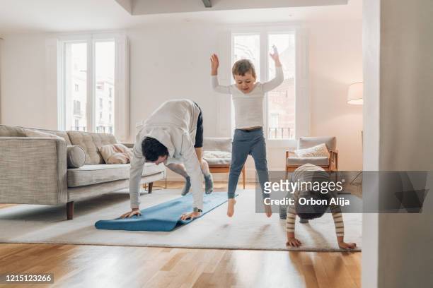 padre con hijos haciendo ejercicio en casa - saltar actividad física fotografías e imágenes de stock